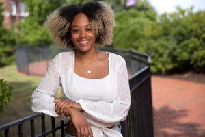 A female student smiles at the camera while leaning against a railing.